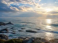 Морський горизонт зі світлом сонця крізь хмари, хвилями, скелями
